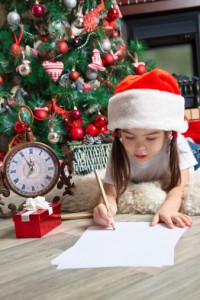 Little girl in hat writes letter to Santa