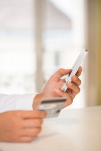 Woman's hands holding credit card and using cell phone